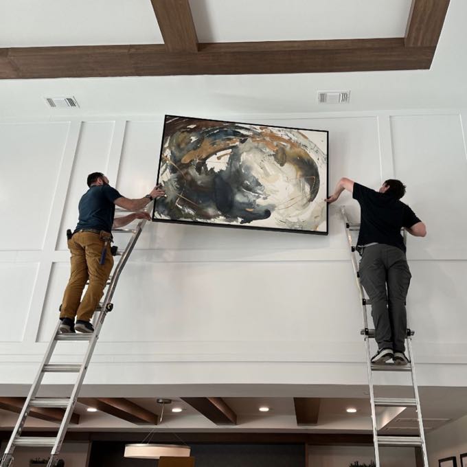 Installers hanging a large painting